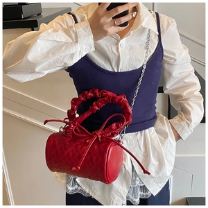 Détail du sac Boston rouge à matelassage cœur avec poignée plissée et chaîne argent