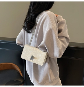 Detail view of cream fish-scale textured crossbody bag with silver chain and metal clasp