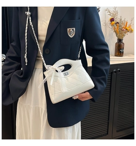 Detail of white quilted bucket bag with lace bow and silver twist lock closure