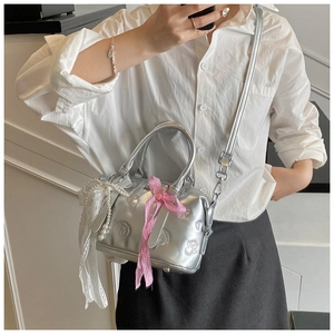 Silver boston bag with floral embossing, pink bow, and pearl lace charm on model