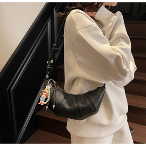 Détail du sac croissant noir avec texture litchi et bandoulière en corde nouée