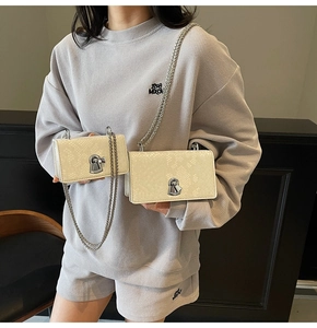 Detail showing contrast between small and large cream snake pattern chain bags on model