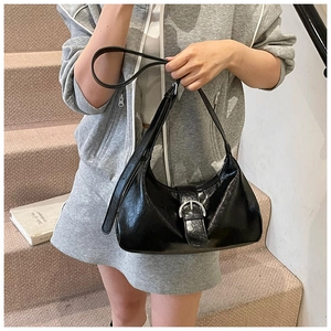 Detail of black glossy hobo bag with pleated texture and silver metal buckle