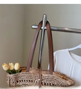 Detail of hollow-out straw woven tote bag with brown leather shoulder straps