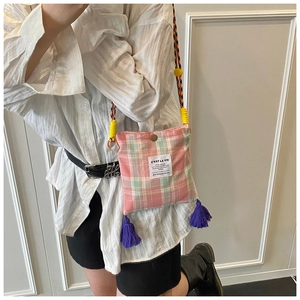 Detail of plaid crossbody bag with colorful woven strap and purple tassels decoration