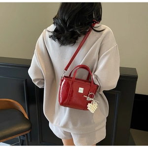 Dettaglio borsa a secchiello in vernice rossa con logo ZSKE e ciondolo cuore di perle