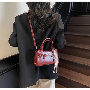 Borsa a mano quadrata in vernice rosso intenso con fiocco e nappa indossata dal modello