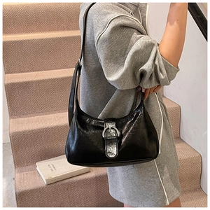 Detail of a black crescent underarm bag with a glossy finish and silver ring buckle