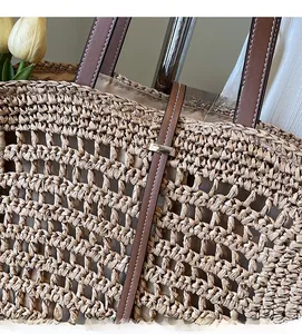 Close-up of hollow straw weave texture and brown leather strap with metal buckle