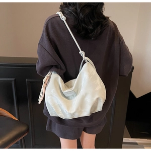 Detailed back view of a light gray hobo bag with a knotted strap on model's shoulder