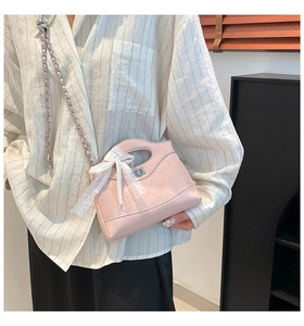 Close-up of pink quilted bucket bag with chain strap and white lace bow detail