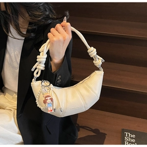 Détail du sac croissant blanc cassé avec texture litchi, anse tressée et breloque perle