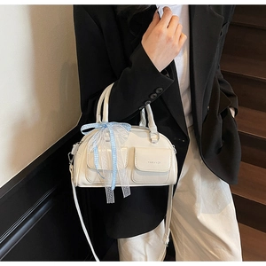Detail of cream Boston bag with blue checkered ribbon and two front flap pockets