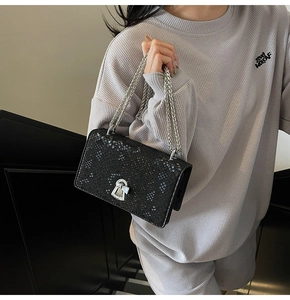 Detail of black snake-textured small square bag featuring silver chain and metal buckle