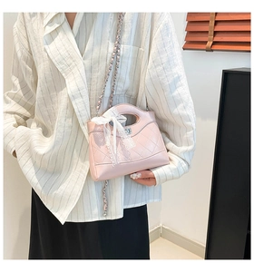 Close-up of pink quilted bucket bag with a delicate white lace bow on the handle