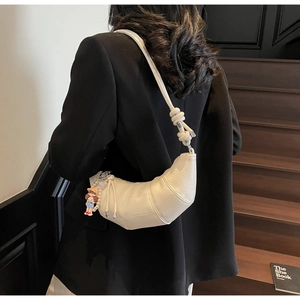 Détail du sac croissant blanc avec texture litchi et breloque de fille de dessin animé