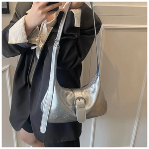 Detail of silver metallic hobo bag featuring a decorative buckle strap and metal eyelets