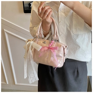 Detail of pink patent leather Boston bag featuring cat paw embossing and lace ribbon décor