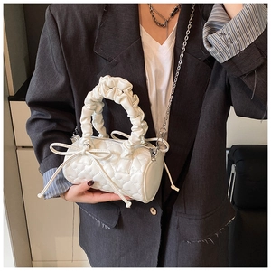 Détails d'un sac Boston blanc matelassé avec poignée à froufrous et nœuds décoratifs