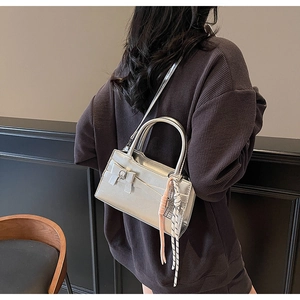 Borsa a mano quadrata argento metallizzato con fiocco e ciondolo intrecciato indossata