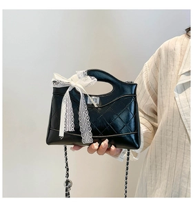 Detail of black quilted bucket bag with lace bow and silver twist lock closure