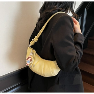 Détail du sac croissant jaune avec texture litchi et pendentif en perles