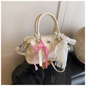 Detail of creamy white Boston bag with embossed patterns, lace charms and pearl chain