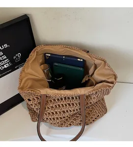 Detail view of large straw tote bag with brown leather handles and spacious inner lining