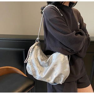 Detail of silver metallic tote bag with long woven tassels and cylindrical shoulder strap
