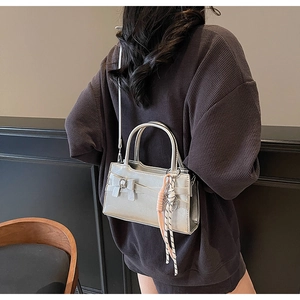 Borsa a tracolla argento metallizzato con fiocco e nappina rosa indossata da modella