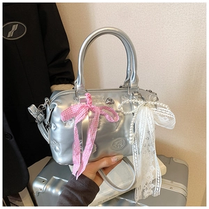 Detailed macro view of silver metallic Boston bag with embossed textures and bow charms