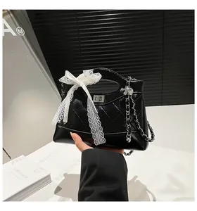 Detailed shot of a black quilted patent leather bucket bag with a white lace bow detail