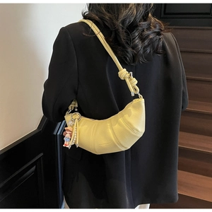 Détail du sac croissant jaune avec texture litchi et breloque poupée avec perles