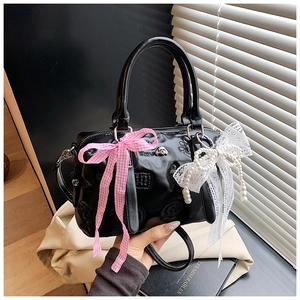Close-up of black glossy Boston bag with cute paw relief and lace pearl bow charms
