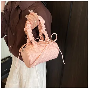 Détail du sac polochon rose à surpiqûres cœurs avec anse plissée et nœud à franges