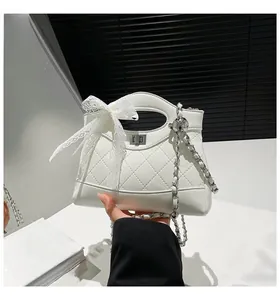 Close-up of white quilted bucket bag featuring a lace bow and silver chain strap