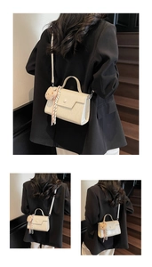 Detailed view of beige crossbody bag featuring envelope flap and cute brown plush bear charm