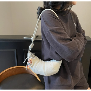 Détail du sac croissant blanc cassé en cuir grainé avec bandoulière à nœuds élégante