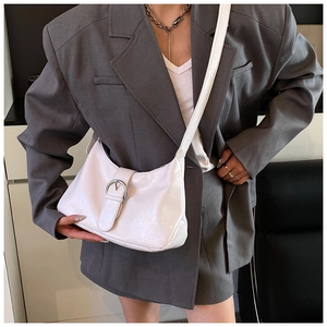 Close-up of a white glossy leather hobo bag featuring a prominent round metal buckle detail