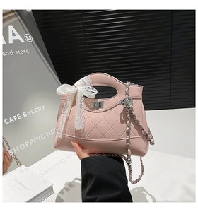 Close-up of pink quilted bucket bag with lace bow detail and metal chain strap