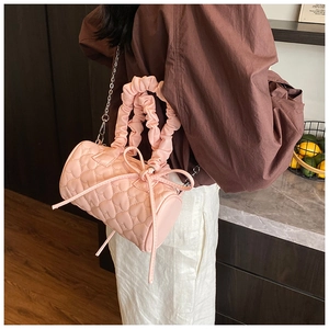 Détail d'un sac cylindre rose matelassé avec poignée à volants et petit nœud