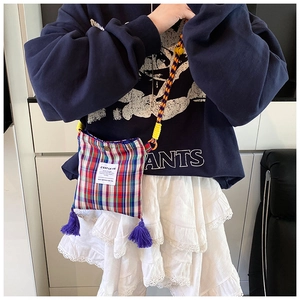 Close-up of retro plaid crossbody bag with colorful woven rope strap and purple tassels