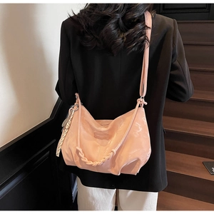 Detail of pink hobo tote bag with woven handle and checkered charm on a stylish model