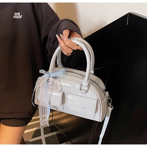 Detail of light blue glossy Boston bag with ribbon and front flap pockets