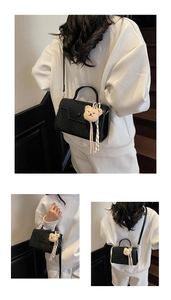Detailed view of black textured square bag with cute bear charm and metal handle strap