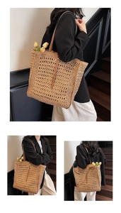 Detail of hand-woven hollow straw tote bag with brown leather straps and texture