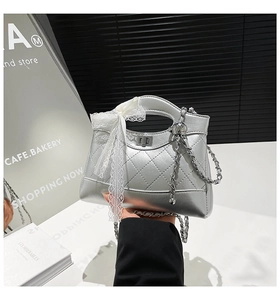 Detail of silver quilted bucket bag with lace bow and leather-braided metal chain strap