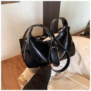 Detailed close-up of glossy black hobo bag with silver zipper and adjustable strap