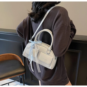 Detail of grey crossbody Boston bag featuring a blue plaid bow and dual front flap pockets