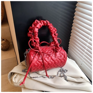 Détail du sac cylindre rouge avec matelassage cœur, nœuds et poignée froncée